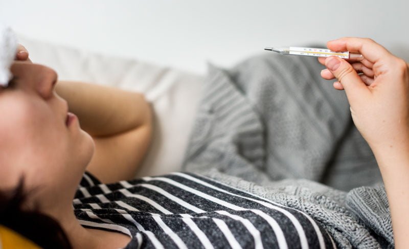 Woman with a cold and high fever, emphasizing its importance in managing Dengue fever symptoms, courtesy of Sentral IVs