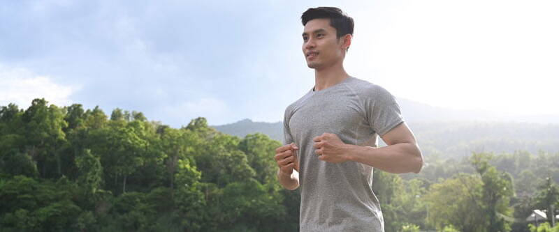 Energetic man jogging in the park at dawn, embodying a healthy lifestyle. Discover the benefits of Strong Defense IV Drip from Sentral IVs for a fortified immune system and enhanced well-being.